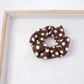Vue détaillée du chouchou en tissu à pois marron sur un plateau d'exposition blanc - Pois Marrons