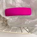 Close-up of a vibrant fuchsia sponge hair clip nestled in white wrinkled paper and a wire basket - Rose Red