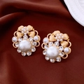 Vue macro de boucles d'oreilles nœuds dorées vintage avec diamants et perles blanches - Or