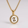 Macro view of gold round pendant with white shell inlay and 3D Z letter detail - Letter Z