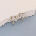 Polished silver star shaped hoop earrings on white stone display with blue background - Silver Star Open Hoop