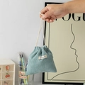 Close-up of gray-blue corduroy drawstring pouch with white cotton ties and fabric label - Grey Blue