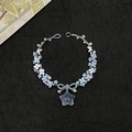 Bracciale intrecciato a mano con perle, fiori blu e ciondolo a stella su sfondo nero - Stile Stella Blu