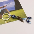 Detail of vintage brass owl keychain with blue evil eye beads on a clean card background - Owl