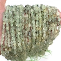 Hand holding natural irregular prehnite tumbled stone necklace in pale green - Prehnite