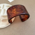 Detailweergave van de brede open hars armband met gepolijste amber schildpadhuid textuur - Klein / Brede Open Stijl / Bruin