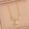 Detailopname van een gouden strikvormige hanger met een glanzende traan-zirkonia - Goud Witte Zirkoon Ketting