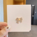 Golden bow brooch pin featuring sparkling rhinestones and a central faux opal stone - Cat Eye Bow