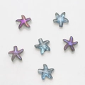 Macro detail of starfish shaped glass crystals with iridescent blue and purple finish - Pack of 30 / Semi-transparent Purple