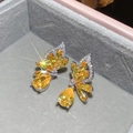 Macro view of wing-shaped yellow gemstone stud earring on gray velvet display - Butterfly Teardrop Style / Yellow
