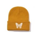 Detailed close-up of white butterfly embroidery on a yellow ribbed knit beanie cuff - One Size / Ginger Yellow