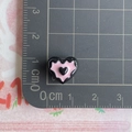 Vista macro de un mini colgante de corazón de resina negra de 1cm con regla graduada - Negro y Rosa