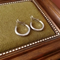 Dettaglio di orecchini a cerchio in argento lucido su cornice vintage e tessuto verde - Cerchio 20mm / Argento