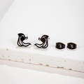 Minimalist abstract black metal stud earrings for women on white textured stone background - Black