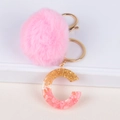 Dettaglio di pompon in pelliccia sintetica rosa e portachiavi lettera C in resina - Lettera C