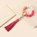 Detail of wooden beaded keychain bracelet with gradient pink tassel on a beige notebook - Rose Red