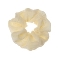 Close-up of pleated fabric scrunchie in pale yellow and cream white for bun hairstyles - Yellow
