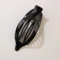 Glossy black oval leaf-shaped hair clip with hollow center on beige background - Bright Black