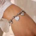 Silver-tone heart charm bracelet with sparkling crystals on a woman's wrist - Silver