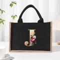 Linen canvas tote bag with black trim and floral gold letter J print in a studio setting - Bronze Floral Letter J