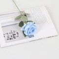 Single realistic velvet blue rose placed on an open magazine for home wedding decor - Silk Sky Blue