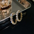 Orecchini a cerchio dorati geometrici con diamanti brillanti su una superficie riflettente - Ago D'argento - Strass Rotondo Bianco