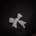 Elegant silver-toned bow brooch with shimmering white zircons on dark fabric background - X0126 Bowknot
