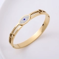 Brazalete calado dorado con borde de engranaje y dije de ojo de demonio azul - Dorado