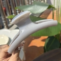 Nahaufnahme einer großen 15cm grauvioletten Haarspange in der Hand bei Sonnenlicht - Extra groß / Zementgrau