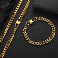 Flat lay of gold Cuban link necklace and bracelet set on a textured black background - Necklace (20 Inch) / Width 6mm / Gold