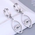 Makroaufnahme von silbernen Evil Eye Ohrringen mit blauem Zirkon auf weißem Kachel - Silber