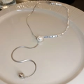 Detalle de collar de perlas plateadas en plato cerámico con cadena de serpiente fina - Estilo de Retazos de Perlas y Metal Cuadrado