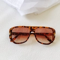 Détail de lunettes de soleil écaillées avec verres dégradés marron sur fond blanc texturé - Imprimé léopard