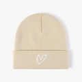 Detail of white heart embroidery on a beige knitted beanie with clear ribbed texture - One Size / Beige