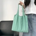 Detail shot of a green and white checkered canvas tote bag held by a model in casual attire - Green Checkered