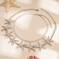 Detail van strandstijl parelketting en zilveren zeester hanger set op zandachtergrond - Zilveren zeester (2-delige set)