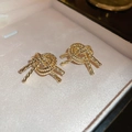 Makroaufnahme goldener Knotenohrstecker in einer rosa Schmuckschatulle aus Metall - 43# Goldene Seilknoten-Stil