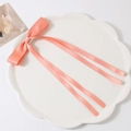 Elegant pink ribbon bow hair clip with long streamers on white lace plate decorative view - Light Orange Red
