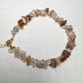 Macro detail of irregular natural quartz crystals with golden lobster clasp and chain - Copper Rutilated Quartz