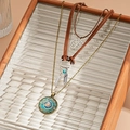 Detail of bohemian layered necklace with mandala and life tree charms on wooden tray - Coffee 3-Layer Set