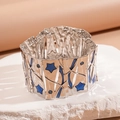 Macro view of wide silver metal bracelet with blue star inlay on white rock - Lake Blue