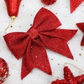 Sparkling red glitter Christmas bow with festive bells and stars on snowy background - Red Medium Bow