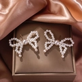 Detailed view of elegant bow-shaped pearl earrings on premium rose gold satin fabric - 3242-Classic Butterfly Studs