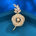 Elegante broche floral dorado con perla melocotón y detalles de hojas de cristal - Estilo Hoja Champán (XD824351)