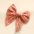 Close-up of cotton floral bow hair clip with detailed orange fabric and print patterns - Orange Floral