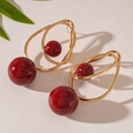 Detalle de pendientes dorados con cuentas de acrílico rojo y diseño de alambre - Oro Rojo (Cuenta Roja/Base Dorada)
