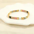 Detailed close-up of Bohemian Tila bead stretch bracelets on a seashell ceramic tray - Pink Gray White Yellow Black Gold
