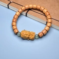 Detail of wooden prayer bead bracelet with carved Buddha charm and green accent beads - Sandalwood 7x8mm Barrel with Clay Statue
