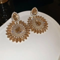 Dettaglio di orecchini a fiore con cristalli a goccia su un piatto di ceramica bianca - Perno in argento - Oro - Giallo