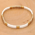 Vue de dessus du bracelet en perles TILA fait main sur une surface en bois naturel - Blanc Or Minimaliste